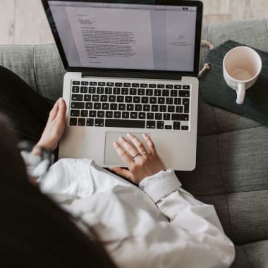 A woman sitting in front of a laptop at a couch